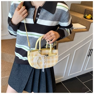 Detail of yellow checkered bucket bag with lace trim and pearl bow charm pendant