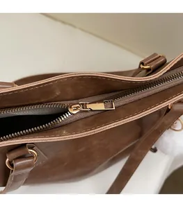 Detailed close-up of smooth gold zipper and premium brown leather on a tote bag