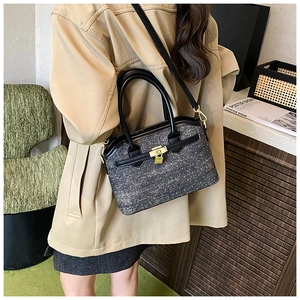 Detail showing the gray tweed bucket bag with black leather straps in a lifestyle setting