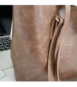Detail of reinforced metal buckle and white stitching on brown leather tote bag