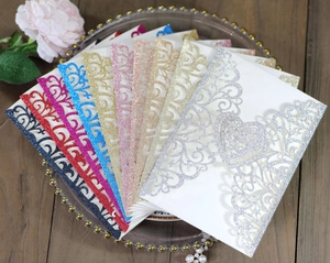 Detail of laser-cut glitter paper wedding invitations with intricate floral heart patterns