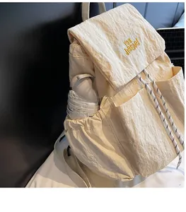 Detail of cream nylon backpack featuring front utility pockets and side umbrella holder