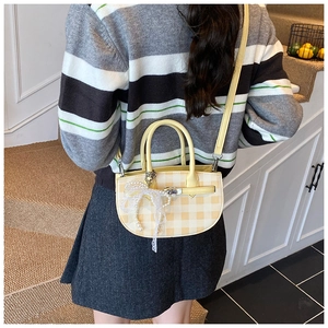 Rear view of a model carrying a yellow checkered crossbody bag with lace bow and pearl charm