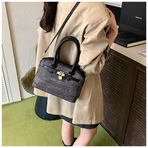 Detail of glittery grey tweed bucket bag with gold lock and black leather strap