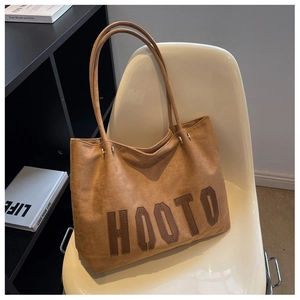 Detail view of brown suede tote bag with HOOTO leather patch and dual slim straps