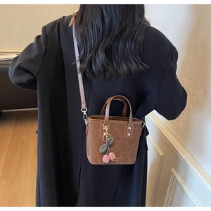 Detail of vintage brown leather bag with marble texture and cherry charm on back of model