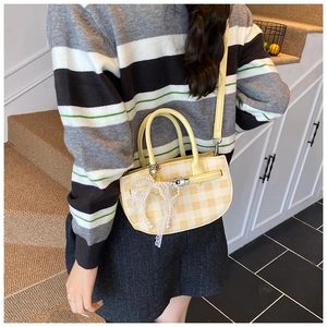 Detail of yellow gingham mini bucket bag featuring white lace bow and pearl charm accents