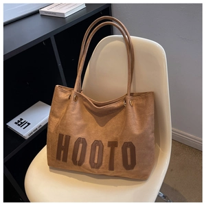 Detail of tan tote bag with HOOTO leather lettering and reinforced gold hardware
