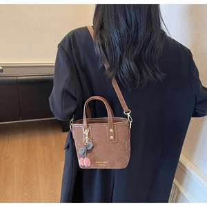 Brown bucket bag with marble texture and cherry charm shown as a crossbody on a model