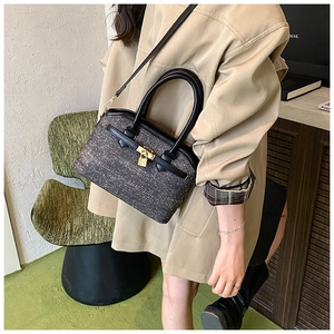 Detailed close-up of grey tweed texture and gold padlock on luxury bucket bag