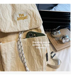 Detail of durable beige backpack front patch pocket showing phone and large capacity