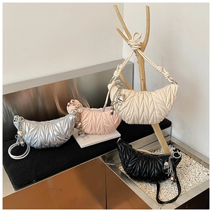 Détail de quatre sacs matelassés en argent, rose, blanc et noir avec breloques coeur