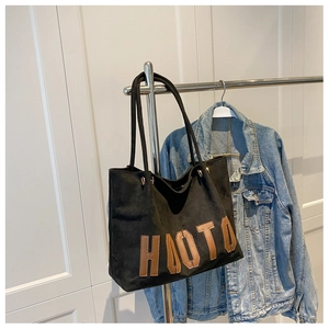 Detail of black suede tote bag with brown HAOTO letter patches on minimalist hanger