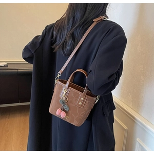 Rear view of brown bucket bag with vintage pattern and cherry charms on a model