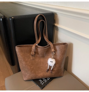 Close-up of brown vintage leather tote bag texture with plush monster charm accessory