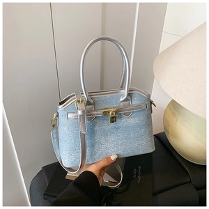 Detail of light blue denim bucket bag with silver handles and iconic golden metal lock