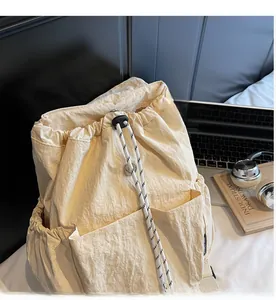 Detail of cream drawstring backpack with striped cord and functional side pockets