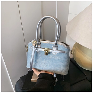 Detailed close-up of light blue denim bucket bag with silver trim and gold padlock accent