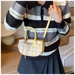 Detail of yellow and beige checkered mini handbag with pearl bow and silver lock clasp