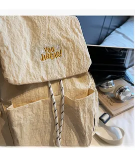 Detail of cream casual backpack showing textured fabric and YOU JIBEAR embroidery