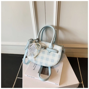 Close-up of blue and white checkered bucket bag with pearl lace charm and metallic clasp