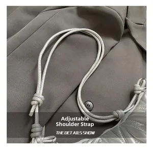 Détail de la bandoulière nouée réglable sur un sac à bandoulière plissé gris argenté