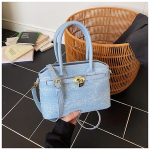 Detail of light blue denim bucket bag with gold padlock closure and adjustable strap