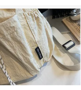 Detail of beige nylon crossbody bag texture with brand label and drawstring buckle