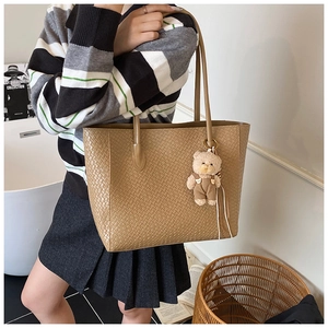 Close-up of khaki woven tote bag texture with a cute bear charm in a home setting