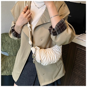 Gros plan détaillé du sac bandoulière blanc plissé matelassé avec pendentif argenté