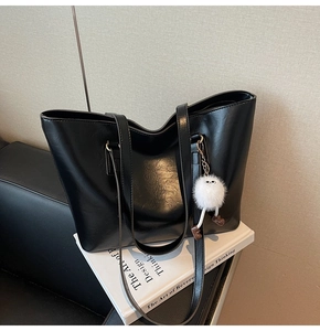 Detail of black faux leather tote bag with soft texture and white monster charm