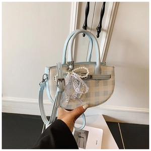 Close-up of light blue checkered handbag with pearl chain and lace bow detail