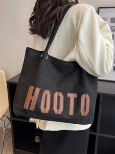 Large black HOOTO tote bag with leather letter patches shown on a shoulder model