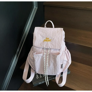 Detail of light purple backpack showing textured nylon fabric and yellow letter embroidery