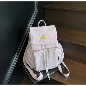 Detail of light pink casual backpack showing embroidery and textured drawstring closure