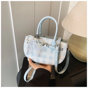 Detail of light blue checkered bucket bag with pearl bow and lace charm decoration