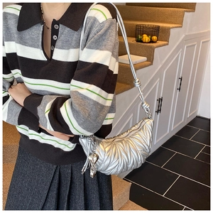 Détail du sac argenté métallisé avec texture matelassée et breloque en forme de cœur