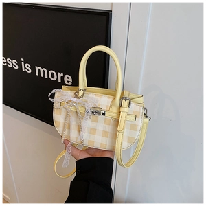 Close-up of yellow checkered bucket bag with pearl lace bow and silver twist lock