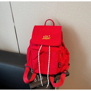 Detail showing the red casual backpack with embroidered flap and drawstrings