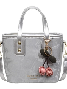 Silver metallic bucket bag with dual handles and cherry charm in a front view display