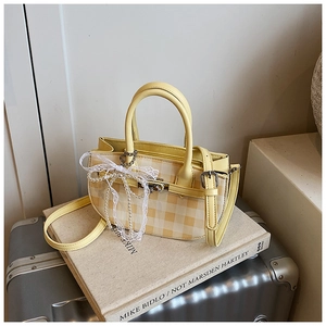 Detail of yellow gingham handbag featuring lace pearl bow and detachable leather strap