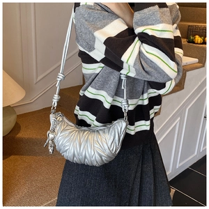 Détail du sac demi-lune argenté matelassé avec breloque cœur et bandoulière nouée