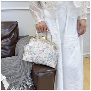 Detailed embroidery on cheongsam bag with bamboo handle and pearl accents