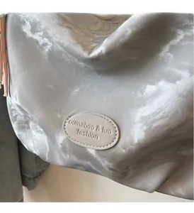 Dettaglio della trama plissettata metallica argentata e patch in pelle sulla borsa