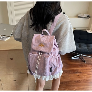 Purple nylon backpack with drawstring closure and yellow embroidery shown on model