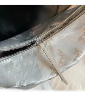 Dettaglio della cerniera in metallo e della trama argento lucido della borsa tote