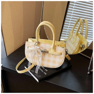Detail of yellow checkered bucket bag with pearl pendant and lace bow charm