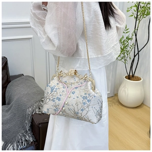 Close-up of vintage floral handbag with pearl handle and golden chain strap details