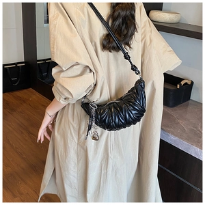 Détail du sac demi-lune noir avec texture plissée et accessoire de chaîne argentée