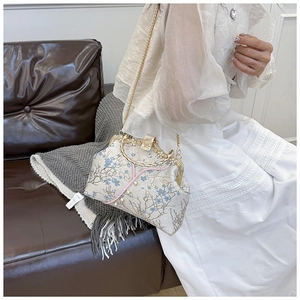 Detailed embroidery of blue floral patterns and pearl clasp on retro metal frame bag